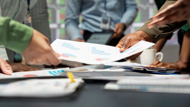 Employees making decisions while looking over company statistics and charts
