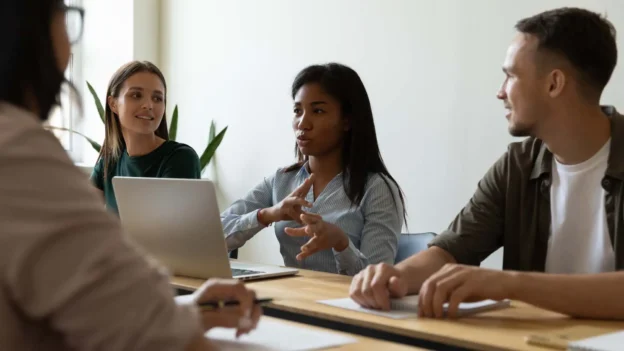 Four business professionals are seated around a table and are having a meeting.