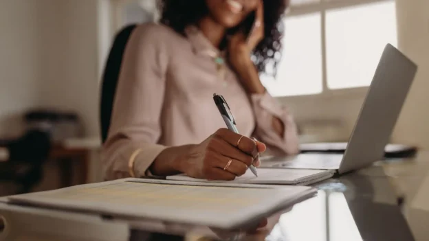 A woman sitting at a desk, writing something down.