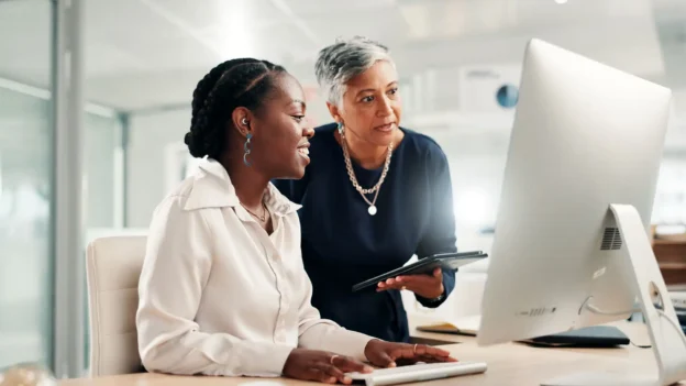 Two women looking at a computer monitor.
