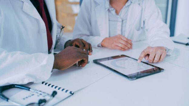 Doctors go over strategy on health records on a tablet