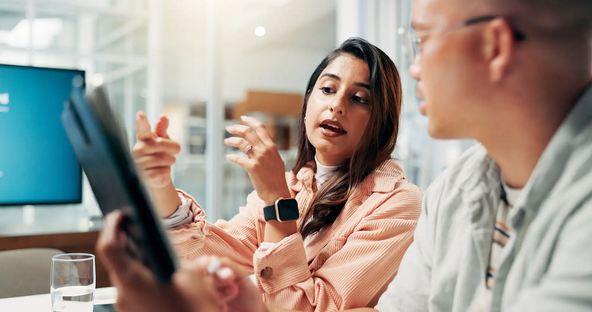 A woman and a man observe information on a tablet. The woman is explaining something to the man.
