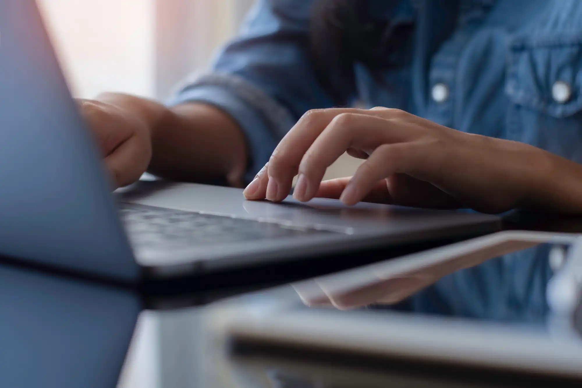 A man sits at a desk, typing on his laptop computer.