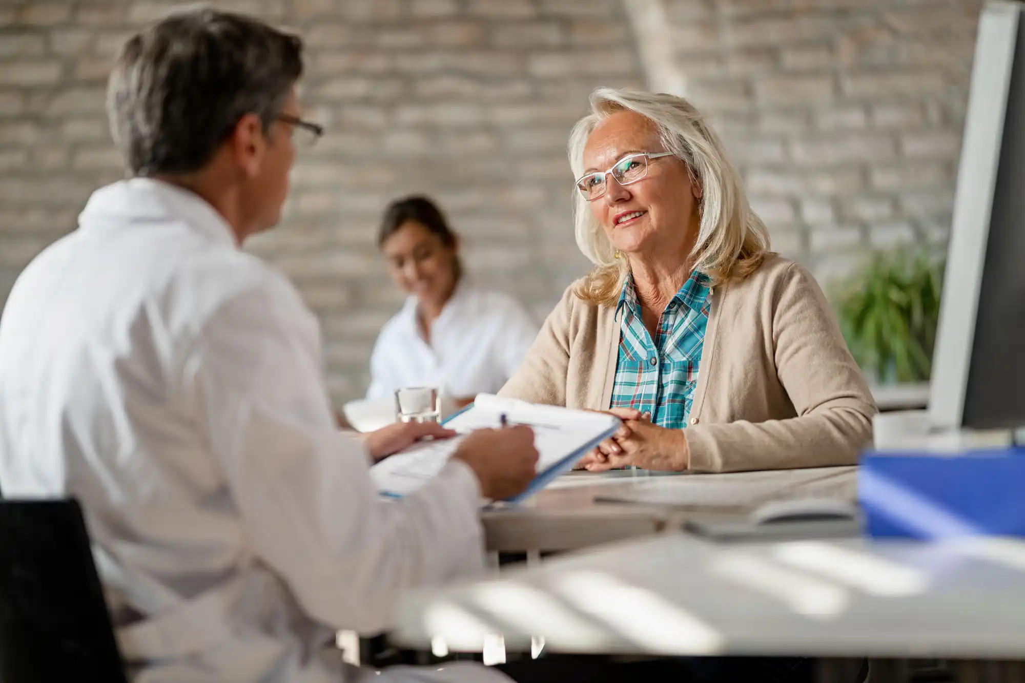 A woman with gray hair converses with a businessman.