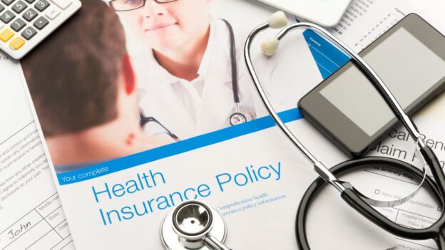 Enrolling for employee benefits with a calculator, phone, booklet, and stethoscope