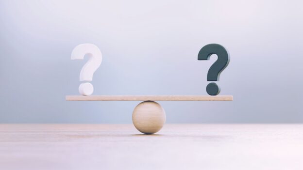 A scale with a rock to balance and two question marks on both sides of the scale