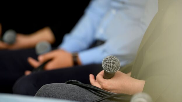 People sitting on a panel holding microphones