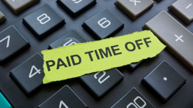 A keyboard with a piece of paper that reads paid time off.