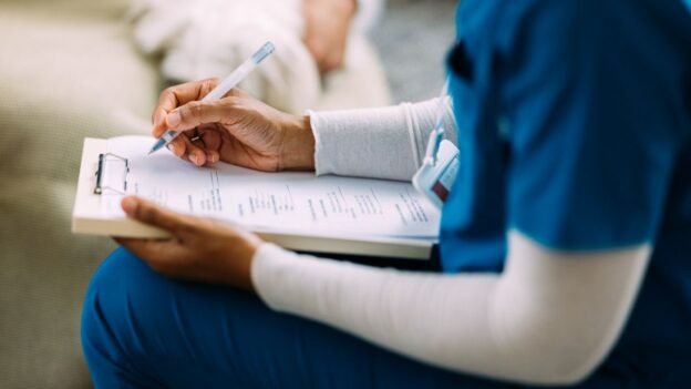 A nurse going over a health plan on a clipboard