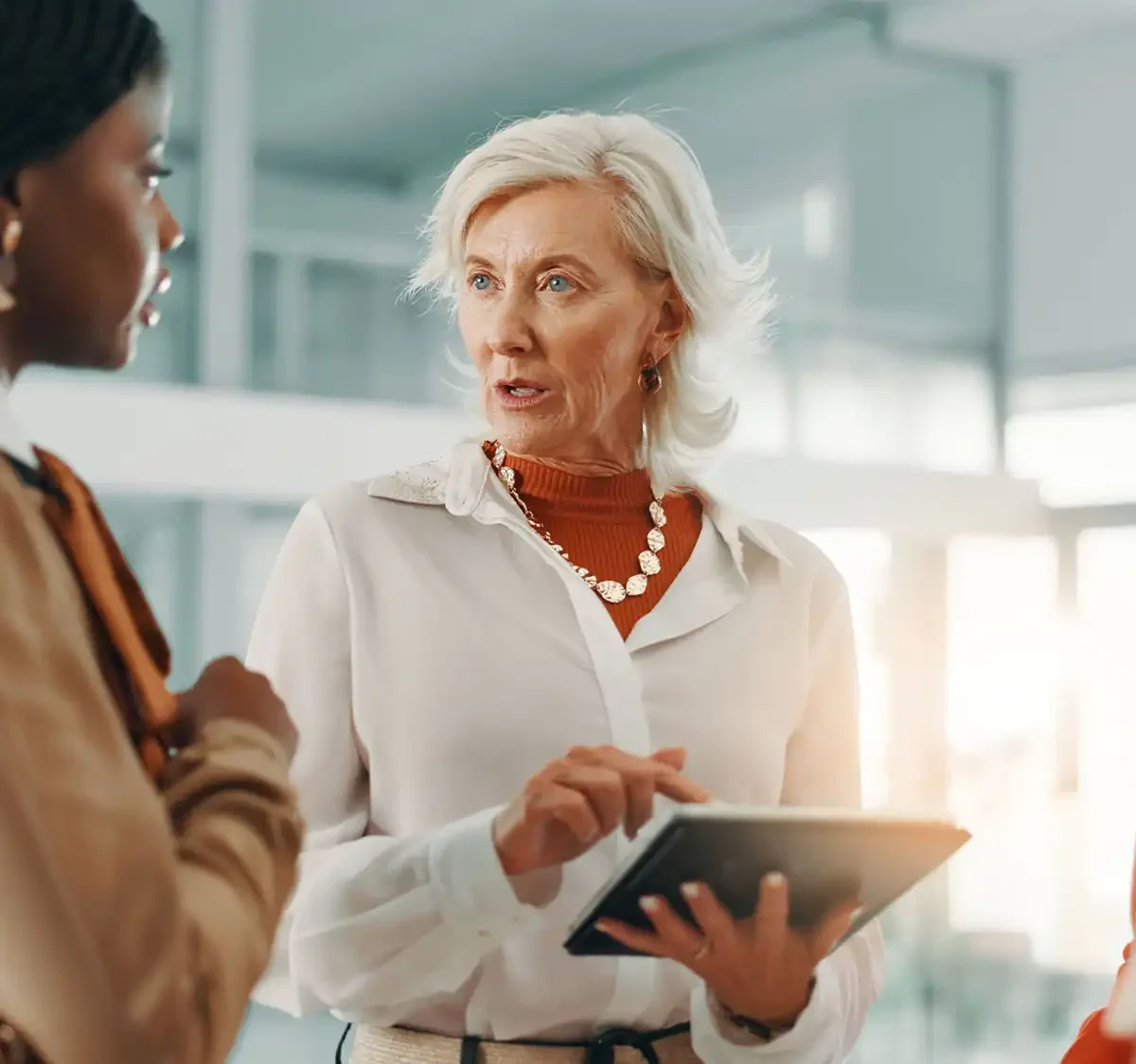A group of business professionals standing in a circle, with one of them giving instructions while holding a tablet.