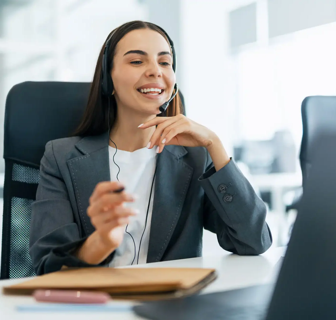 A smiling representative wearing a headset provides support to a customer via video call.