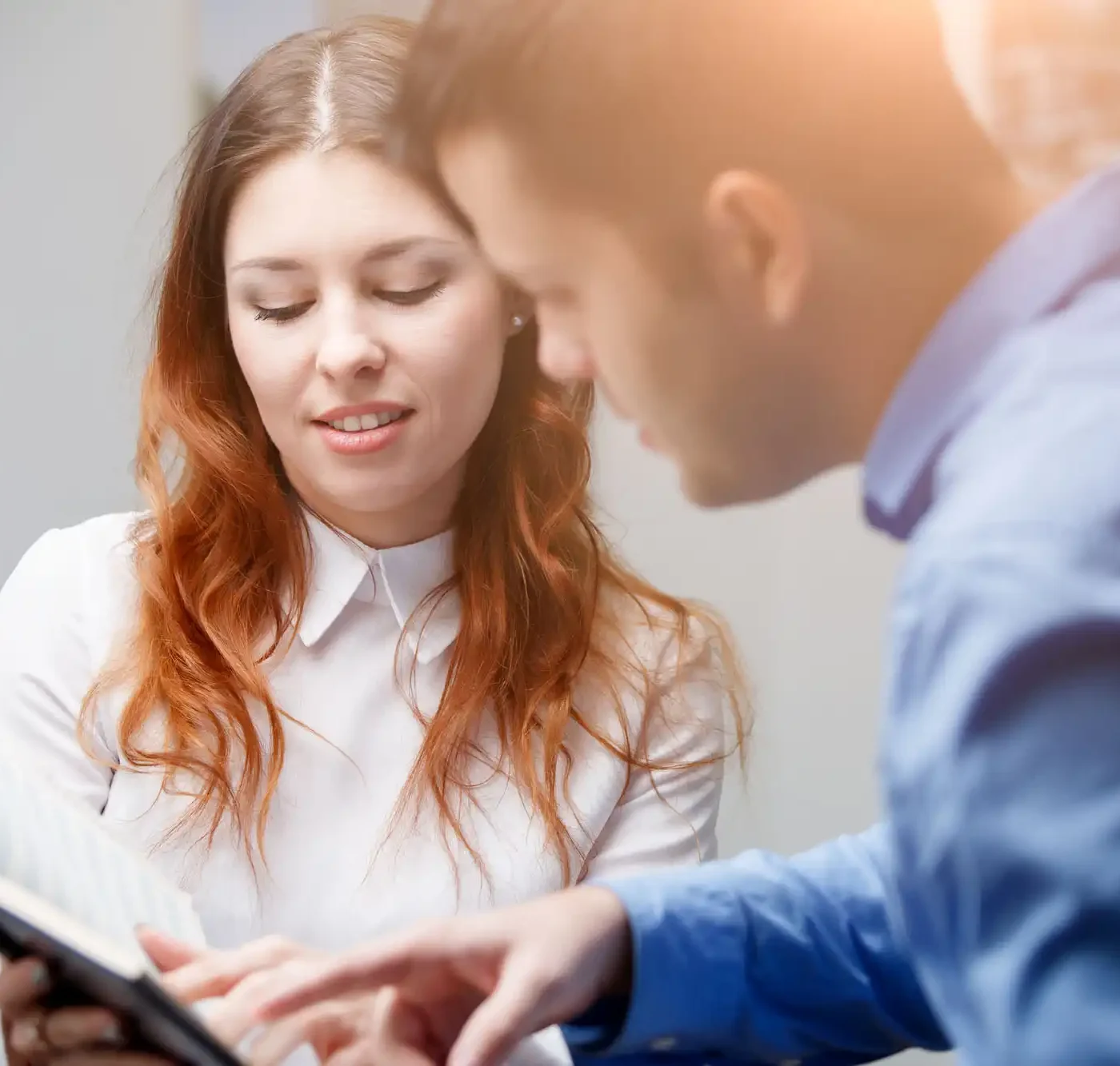 A woman and a man in an office interpreting information from a notepad.